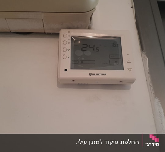 תרמוסטט מזגן על קיר עם תצוגת טמפרטורה